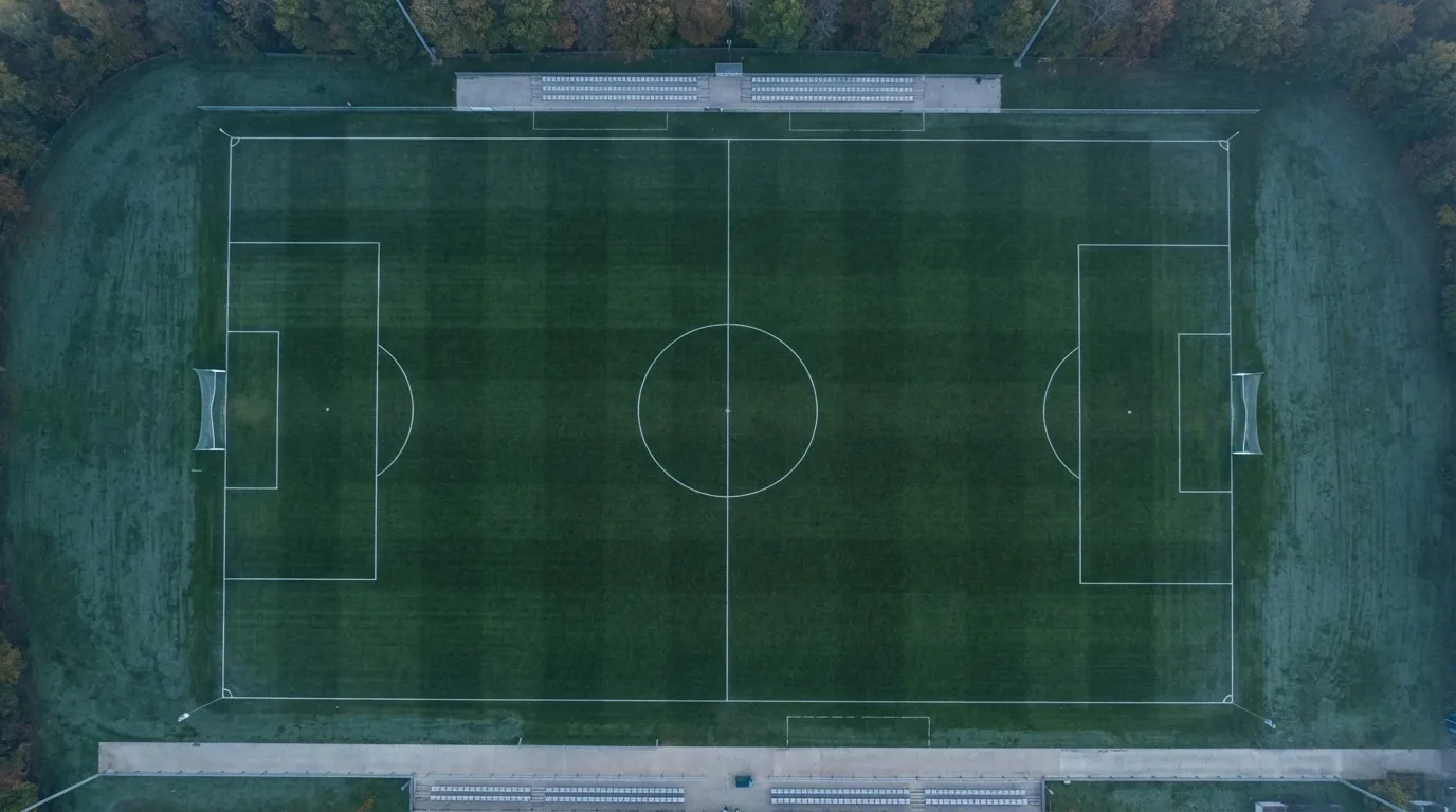 Ein Fussballplatz von oben gesehen, die Linien bilden ein helles Muster auf dem Rasen, Drohnenperspektive in der Morgendämmerung.